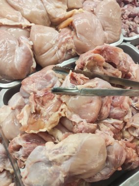 Buzdaki bir yığın tavuğun fotoğrafı. Taze kesilmiş tavuk etin tazeliğini korumak için bir dükkan vitrininde buzla sergilenir. Çiğ gıda malzemelerinin geçmişi