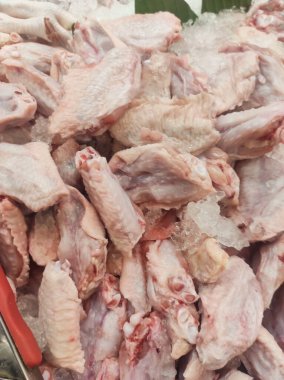 Buzdaki bir yığın tavuğun fotoğrafı. Taze kesilmiş tavuk etin tazeliğini korumak için bir dükkan vitrininde buzla sergilenir. Çiğ gıda malzemelerinin geçmişi