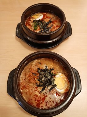 Bir çömlekte iki kase baharatlı miso ramen. Tipik bir Japon şehriye çorbası tabağı, yarı haşlanmış omega yumurtası, nori parçaları ve baharatlı sosla kaplı et parçaları..