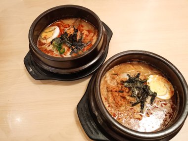 Bir çömlekte iki kase baharatlı miso ramen. Tipik bir Japon şehriye çorbası tabağı, yarı haşlanmış omega yumurtası, nori parçaları ve baharatlı sosla kaplı et parçaları..