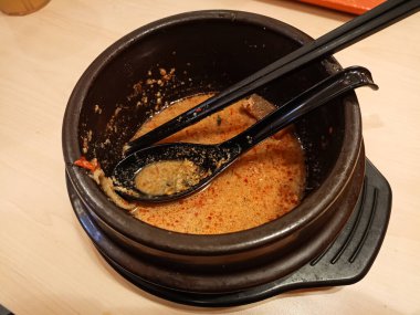 Çubuklu ramen çorbası ve kilden yapılmış bir kaşıkla dolu boş bir kasenin yukarıdan görünüşü. Bir restoran müşterisinden kalan baharatlı ramen çorbası..