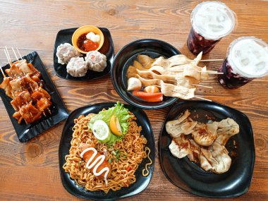 Baharatlı erişteler, biberli yağlı börekler, şiş balıklı kekler, karidesli börekler ve iki bardak soğuk içecek. Masada ziyafet