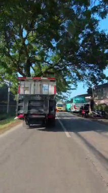 Bandung, Endonezya. 4 Şubat 2026. Güneşli bir sabahta bir otoyolda kamyon ve motosikletlerin yanından geçerken çekilmiş dikey FPV videosu. 4k HD çözünürlükte motosiklet sürerken POV görüntüleri.