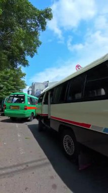 Bandung, Endonezya. 20 Şubat 2026. Şehrin ortasında toplu taşıma araçları tarafından engellenirken motosiklete binmek. Bandung şehir merkezinde yoğun trafik var. 4K HD Çözünürlük Dikey