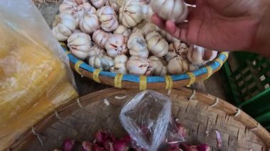 İlk Sinema Kişisi POV: Endonezya 'nın Bandung kentindeki geleneksel bir pazarda bambu tepsiler üzerine istiflenmiş çiğ beyaz sarımsak soğanları seçmek. POV 4K çözünürlüklü geleneksel bir pazardan alışveriş görüntüsü.