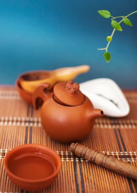 Çaydanlık, çay bardağı ve çay yaprakları bir bambu hasır üzerinde