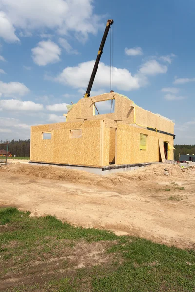 Строительство каркасного дома. Вид на новостройку с журавлями на фоне голубого неба — стоковое фото