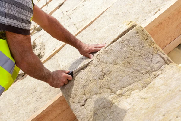 Roofer builder arbetaren installera taket isoleringsmaterial på nytt hus under uppbyggnad. Skärande rockwall med vass kniv — Stockfoto