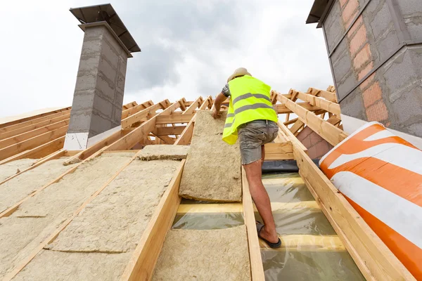 Trabajador constructor Roofer instalación de material de aislamiento del techo (lana de roca) en la nueva casa en construcción —  Fotos de Stock