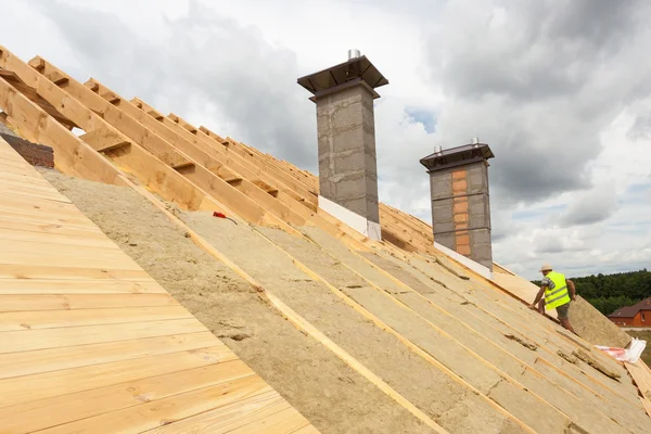 Travailleur du constructeur de toitures installant un matériau isolant pour toiture (laine de roche) sur une maison neuve en construction — Photo