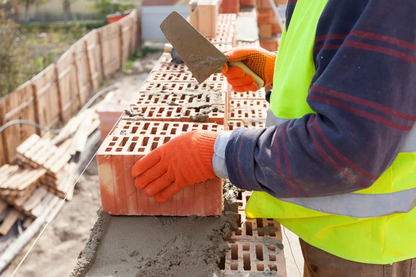 Construction mason worker bricklayer installing red brick with trowel putty knife outdoors — Stock Photo, Image