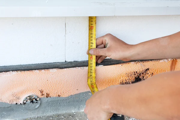 Thermal insulation house foundation walls with styrofoam boards. Worker use ruller to measure the  correct length of styrofoam