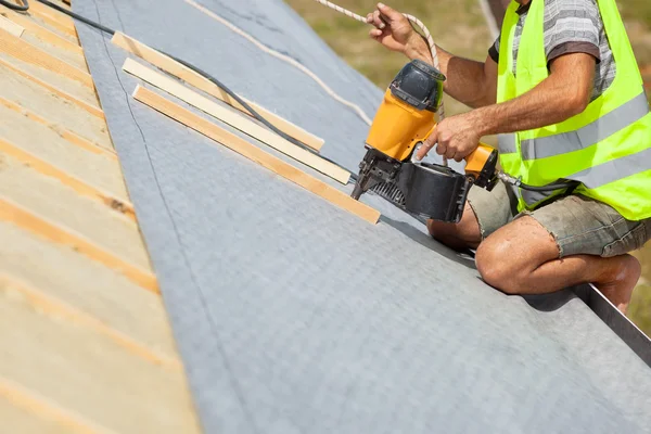 Trabalhador construtor de telhados usar nailgun automático para anexar membrana de cobertura — Fotografia de Stock