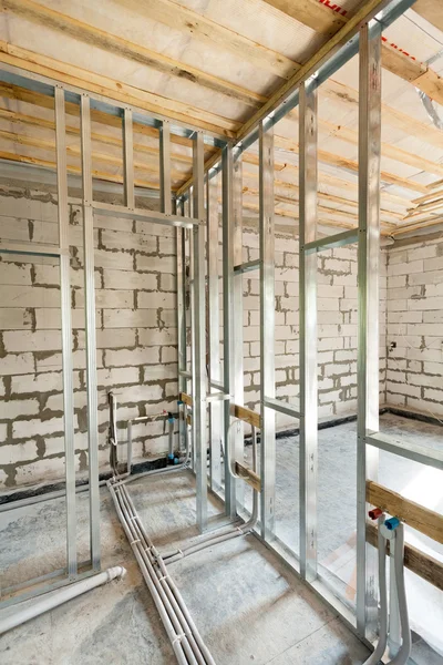 Metal profile frame for plasterboard walls and pipes with valves of a heating system in the house — Stock Photo, Image