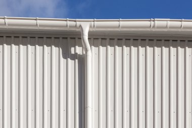 Yeni beyaz yağmur oluk beyaz metal levha mavi gökyüzü ile bir bina