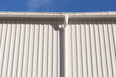 Yeni beyaz yağmur oluk beyaz metal levha mavi gökyüzü ile bir bina