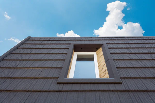 Окно на крыше нового деревянного дома против голубого неба — стоковое фото