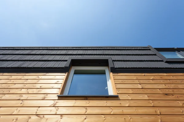 Janela do telhado na nova casa de madeira contra o céu azul — Fotografia de Stock