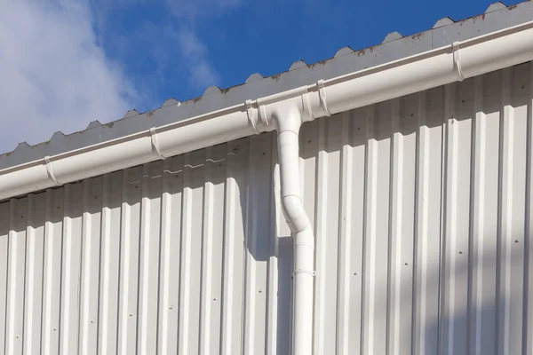 Ny vit Hängränna på en byggnad med vit metall blad mot blå himmel — Stockfoto