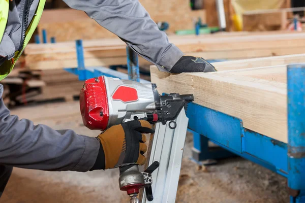 Κατασκευάζει ένα τείχος για σπίτι πλαίσιο. Εργαζόμενος Χρησιμοποιήστε πλαισιώνοντας Nailer να επισυνάψετε ξύλινα δοκάρια — Φωτογραφία Αρχείου