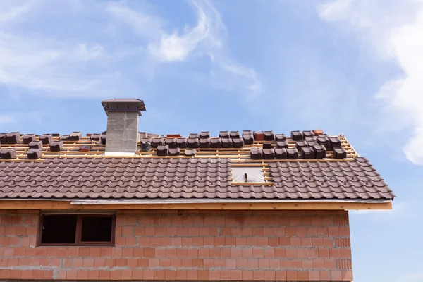 Un techo con chimenea en construcción con pilas de tejas listas para sujetar — Foto de Stock