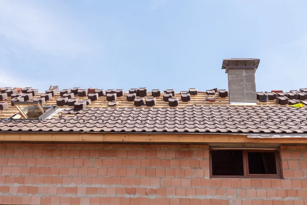 Un toit avec cheminée en construction avec des piles de tuiles de toit prêtes à fixer — Photo