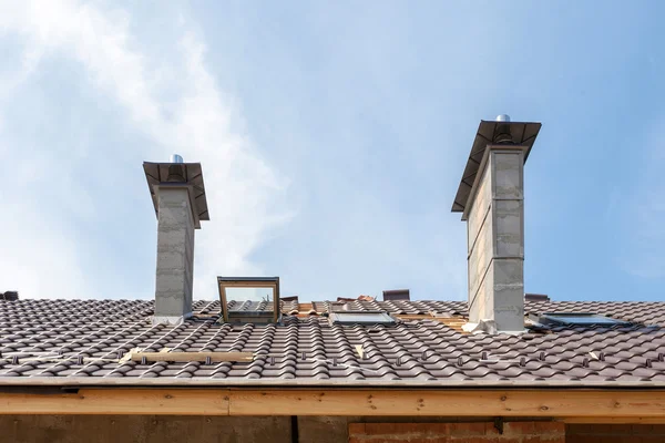 Casa en construcción. Instalación de tejas. Nuevo techo con tragaluz y chimeneas — Foto de Stock