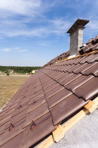 Un toit en construction avec des piles de tuiles de toit prêt à se fixer — Photo