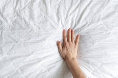 Top view of woman hand testing white orthopedic mattress on firmness. Cropped view of female pressing hypoallergenic foam surface to check its softness at copy space background clipart
