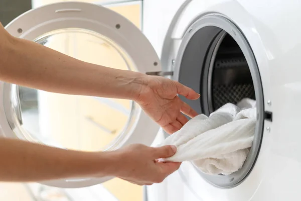 여인이 빨래를 깨끗하고 수건을 나온다 가정주부가 집에서 빨래를 현대식 세탁기를 — 스톡 사진