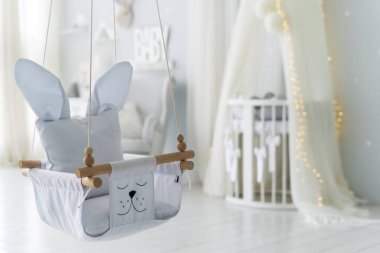 Beşik yataklı yeni doğmuş bebek için yatak odasındaki salıncağa odaklan ve arka planda bulanık fotokopi çek. Hafif minimalist iç mekanlı çocuk odası