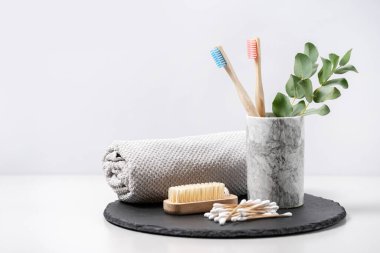 Çevre dostu ve biyolojik olarak bozunabilir nesneler kavramı. Banyo malzemeleri, tırnak fırçası, bambu diş fırçası, tahta kulak çubukları, rulo havlu ve okaliptüs, beyaz fotokopi alanı arka planına karşı.