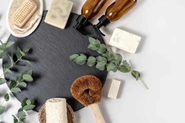 Biyolojik gübrelenebilir nesneler kavramı. Düz uzanış, organik luffa süngeri, doğal sabun, hindistan cevizi fırçası, cam şeker şişesi, okaliptüs bitkisi beyaz fotokopi alanı arka planına karşı ayakta duruyor