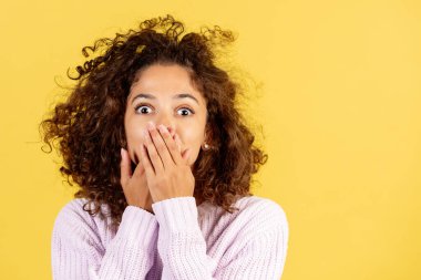 Ne heyecanlı bir haber. Kimseye bir şey söyleme. Şok olmuş genç Afro-Amerikan kadının portresi gözlerini dikiyor, sır saklıyor, elleri ağızda, sarı fotokopi çekilen arka planda duruyor.