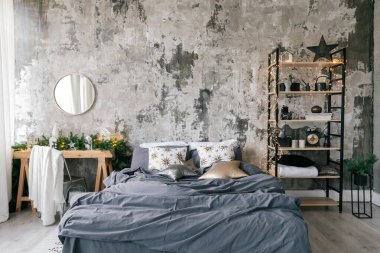 Cozy bedroom in modern design apartment with loft style interior, winter home decor on wooden table, comfortable bed, rack and rustic copy space wall in room