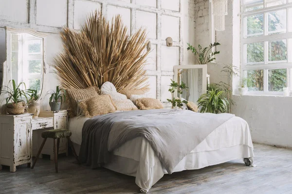 舒适的居室侧视图 室内设计为波希米亚风格 舒适的床 绿屋植物 靠近壁炉架和镜子的家居装饰 阳光和明亮的早晨在房间里 — 图库照片