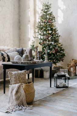 Örgü sepetine odaklan. Yeni yıl ağacına karşı ekose ve bulanık arkaplan. Kış dekorlu, rahat kanepeli ve sehpalı rahat oturma odasının dikey fotoğrafı.