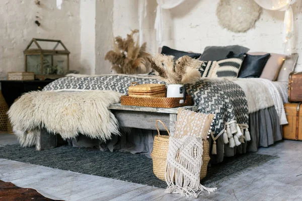舒适的卧室 内饰舒适 靠近舒适床的地毯 格子布 枕头和毛毯 木制长椅 花瓶里的干植物 柳条篮里的家居装饰 — 图库照片