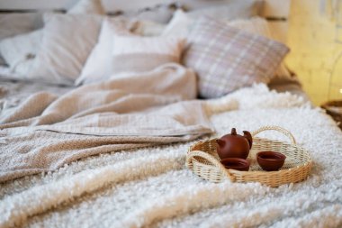 Kahvaltı tepsisine ve çaydanlıkta çin çaydanlığının olduğu seçmeli bir odak noktası. Sabahları yatakta fincanların yanında duruyor. Konforlu yatak odası ve modern apartmanda iç tasarımın moda objeleri.