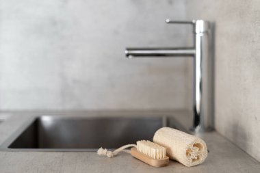 Çevre dostu bulaşık süngeri ve ahşap fırça mermer tezgahın üzerinde, bulanık arka planda boş lavaboya karşı. Geri dönüştürülmüş temizlik malzemeleriyle modern mutfak