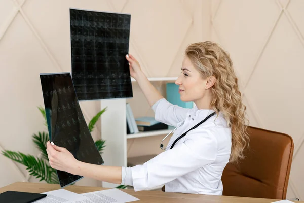 女医生正在研究脑部的X光或磁共振扫描 身穿白色制服 带听诊器的专业医生 坐在现代诊所的办公室里 健康检查 保险概念 — 图库照片