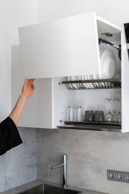 Modern mutfak beyaz dolapları üzerinde duran kadın dikey kırpılmış görünümü, pahalı kaldırma mekanizması ile açık kapı