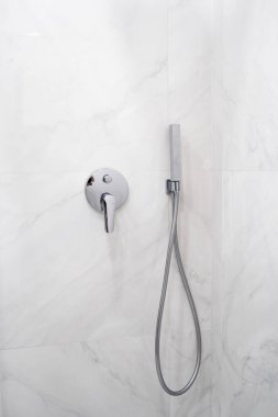 Duş kabininde yeni krom tesisatların dikey görüntüsü ve duvarında fotokopi alanı var. Duş başlığının yanında parlak modern banyodaki seramik fayanslı duvarın üzerinde.