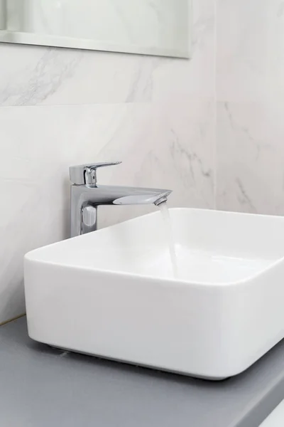 现代浴室白色瓷砖墙边有铬水龙头的水槽垂直视图 旅馆和公寓内部概念 — 图库照片