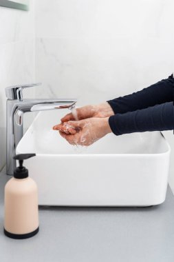 COVID-19 önlemi için ellerini nasıl yıkayacağını. Dikey kesilmiş kadın görüntüsü avuçlarını ve parmaklarını antibakteriyel sabunla sıcak suyla yıkıyor. Kadın evde hijyen prosedürü uyguluyor.