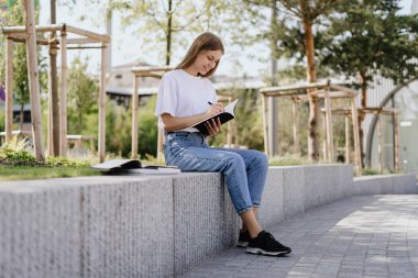 Ders ve dersler için ödev hazırlayan, kitapların sayfalarını ya da kitaplarını egzersizle çeviren genç akademi öğrencisinin tam boy görüşü