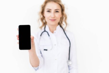Dijital akıllı telefon. Kadın ellerinde görüntüsü var. Medikal ceketli aile doktorunun elinde boş ekranlı modern bir cihaz ve reklam ürünleri için kopyalama alanı tutarken seçici bakış açısı