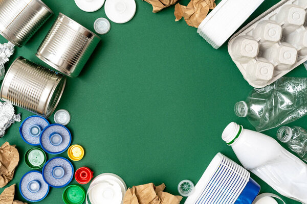Спаси природу. Вид сверху на различные виды мусора и лотков, таких как бумага, пластик и металл на зеленом фоне с копировальным пространством. Концепция переработки, экологии и сортировки отходов
