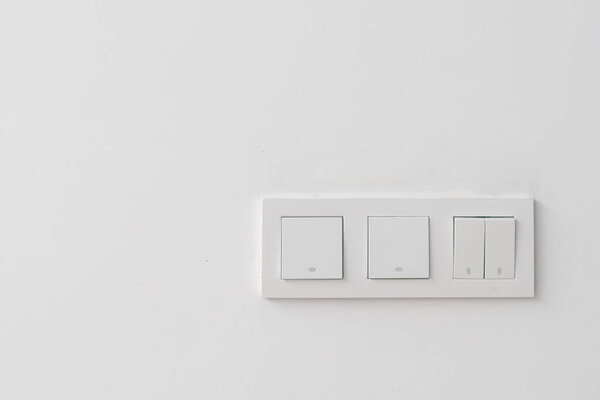 Closeup of white light switches in one plastic frame in minimalistic style on white wall of hotel or office, copy space for text