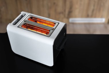 Tipik modern elektrikli, arka planı bulanık, siyah tezgahın üzerinde iki dilimli bir tost makinesi. Yemek pişirme aygıtı konsepti